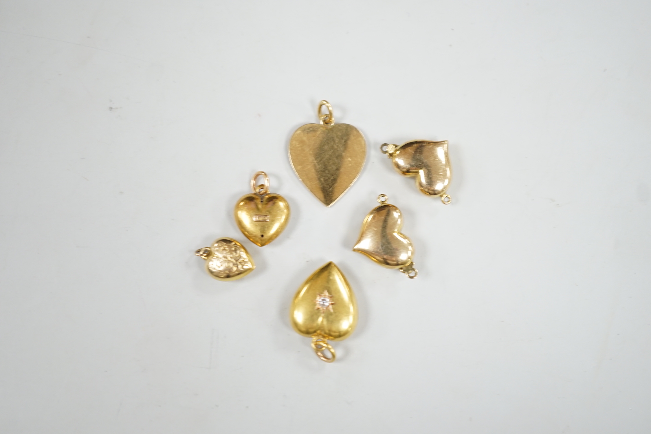 Two late Victorian 15ct and single stone diamond set heart pendants, largest 19mm, gross weight 3.1 grams, four other yellow metal heart shaped pendants including one with green enamel.